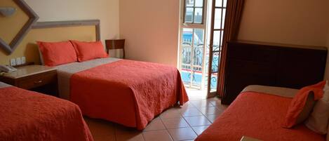 A hotel room with two beds, a large window, and a view of the outside.