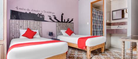 A hotel room with two beds, a bathroom, and a wall mural.