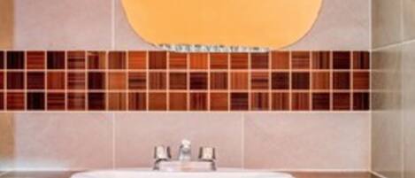 Baño con lavamanos, espejo y salpicadero de azulejos.