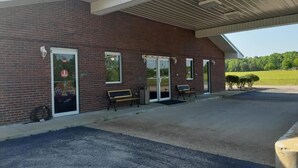 A brick building with a covered entrance, two benches, and a Coca-Cola advertisement. - Deerfield Inn (Parsons)