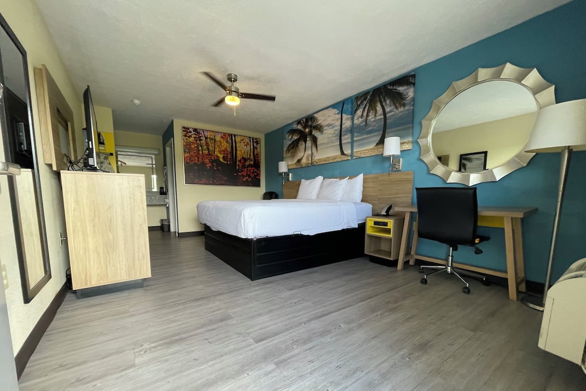 A hotel room with a bed, desk, chair, and a ceiling fan.