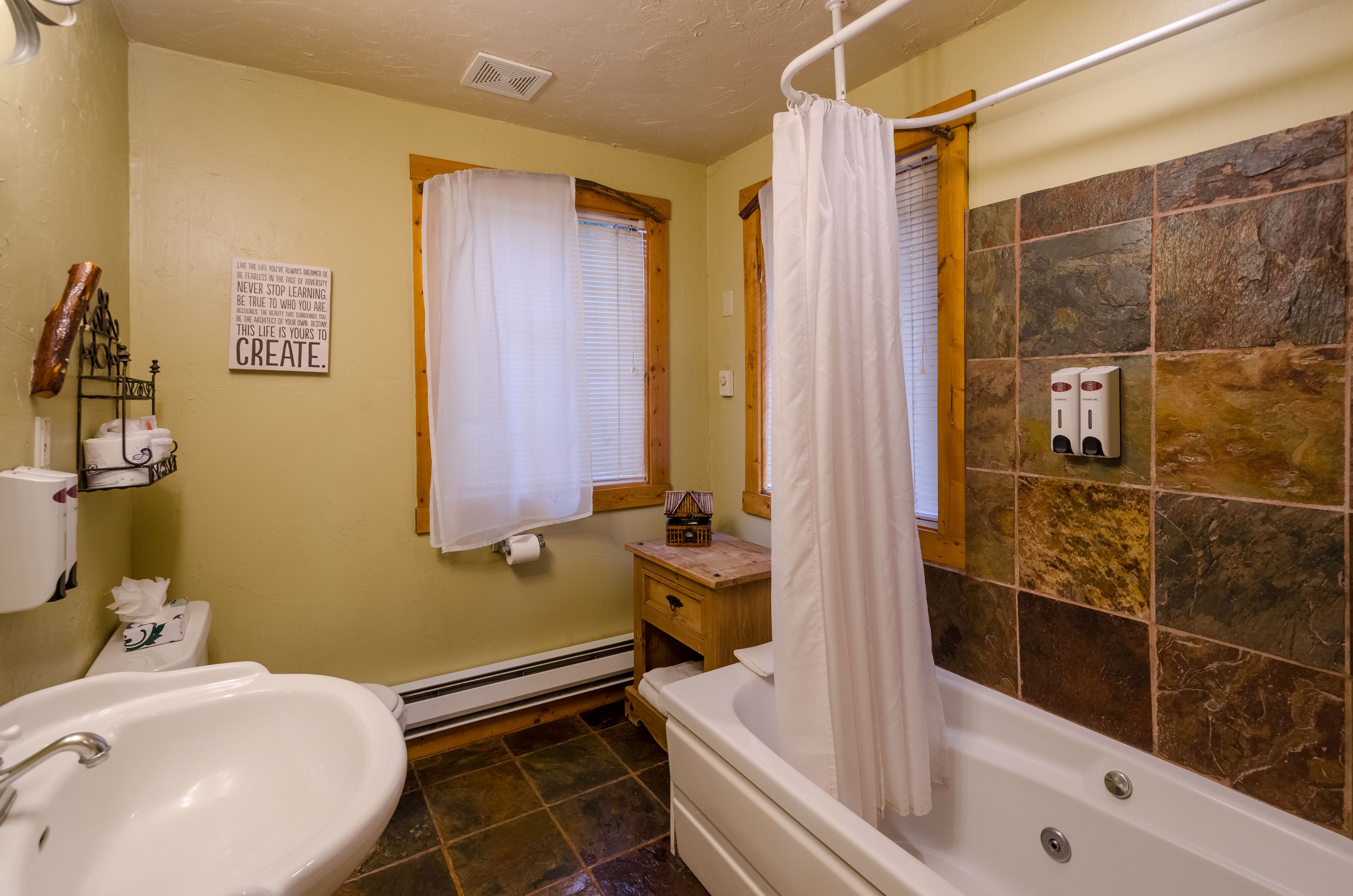 Une salle de bain avec une baignoire, un lavabo, une fenêtre avec un rideau, un porte-serviettes et un panneau sur le mur.