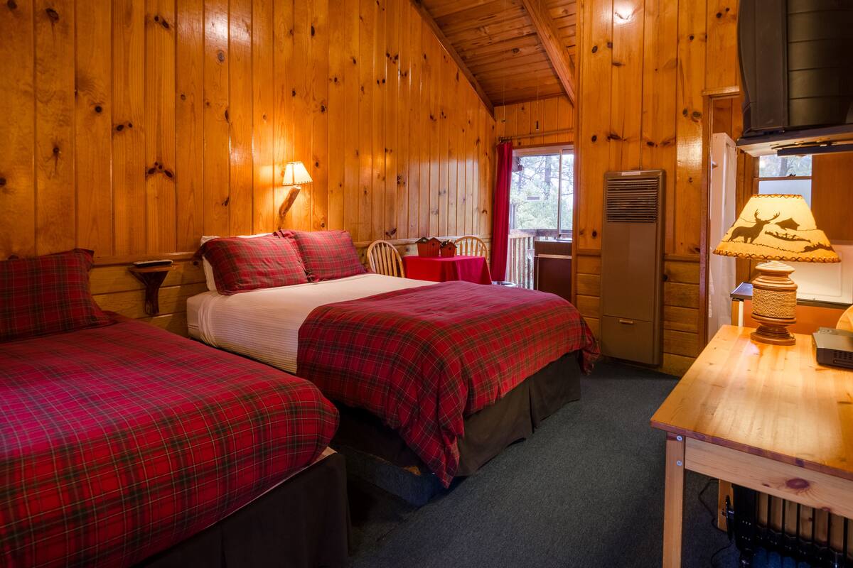 A cabin with two beds, a dining table, and a window with a view.