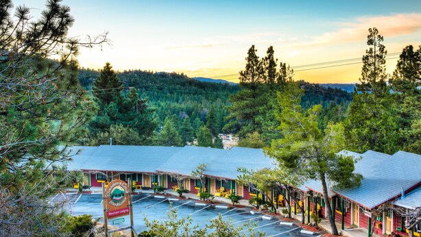 A motel with a red exterior, multiple rooms, and a parking lot. - Idyllwild Bunkhouse (Idyllwild)
