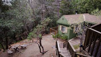 A cabin with a dirt path leading to a wooden deck and picnic table.