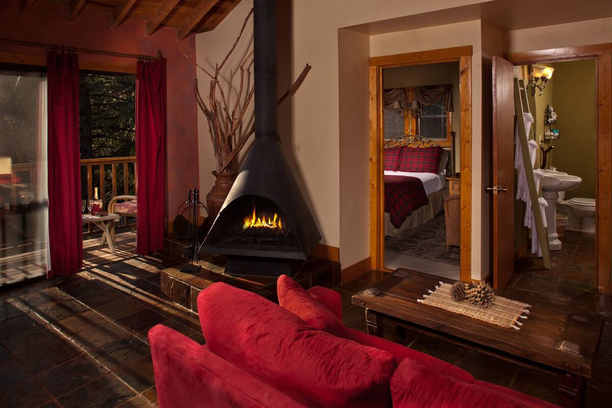 A cozy living room with a fireplace, red curtains, and a red sofa.