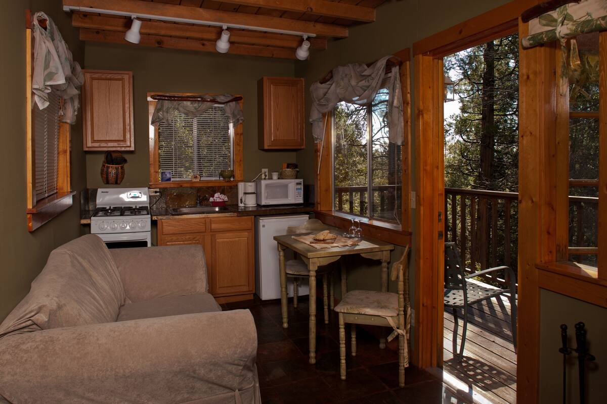 A cozy kitchen with wooden cabinets, a stove, a microwave, and a dining area with a table and chairs.