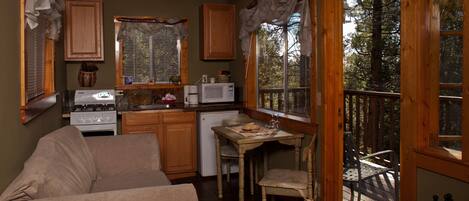 A cozy kitchen with wooden cabinets, a stove, a microwave, and a dining area with a table and chairs.