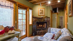 A cozy living room with a stone fireplace, a wooden ceiling, and a comfortable couch. - Idyllwild Bunkhouse (Idyllwild)