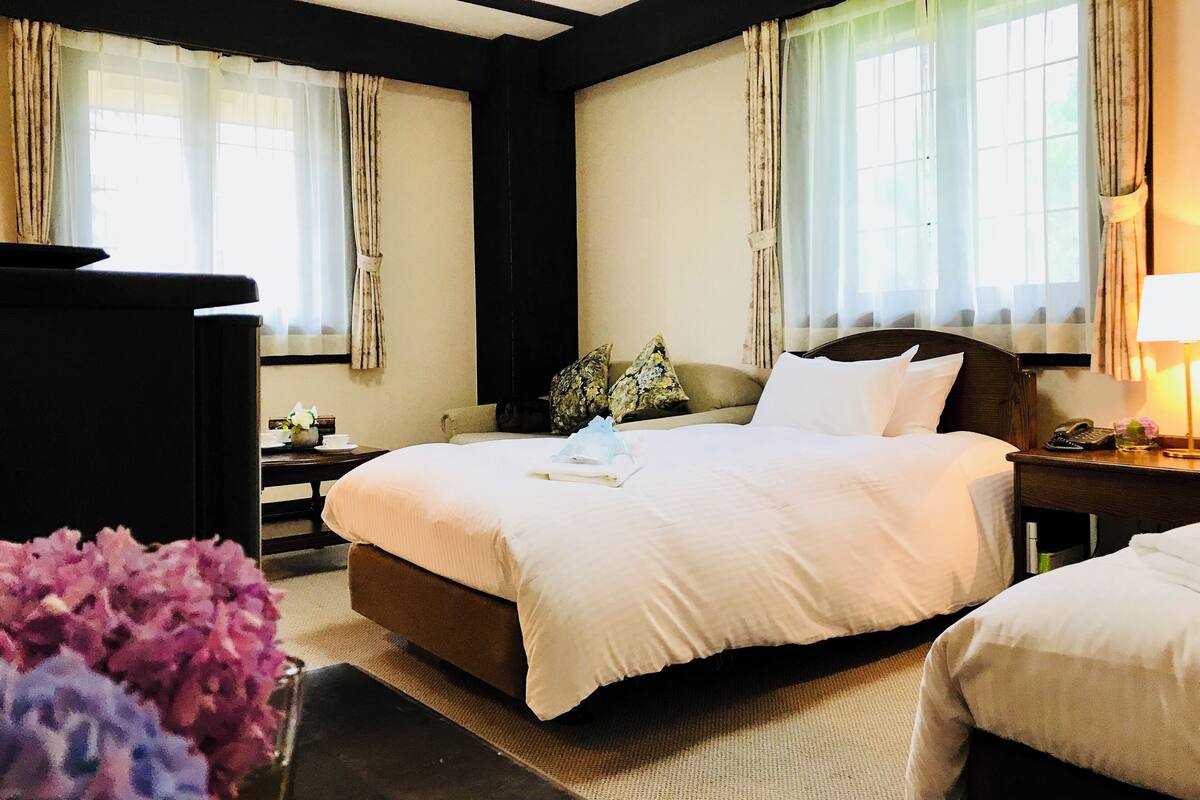 A hotel room with a large bed, a nightstand, a desk, and a chair.