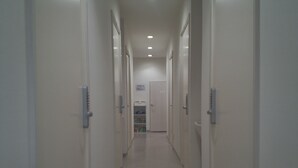 Un pasillo largo y estrecho con puertas a ambos lados, que conduce a una habitación al final.