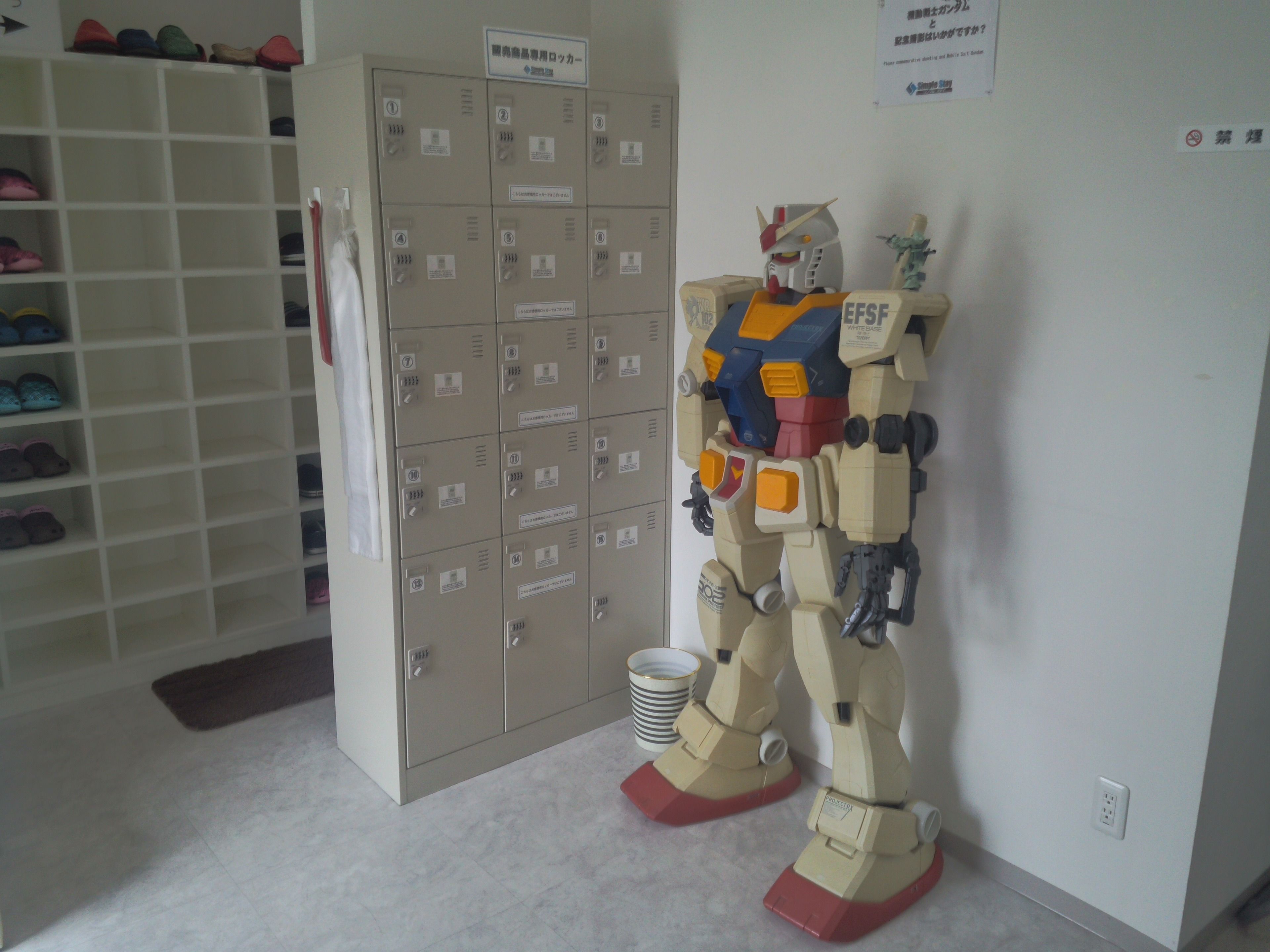 Una habitación con un zapatero grande, una pared de casilleros y una figura de robot.