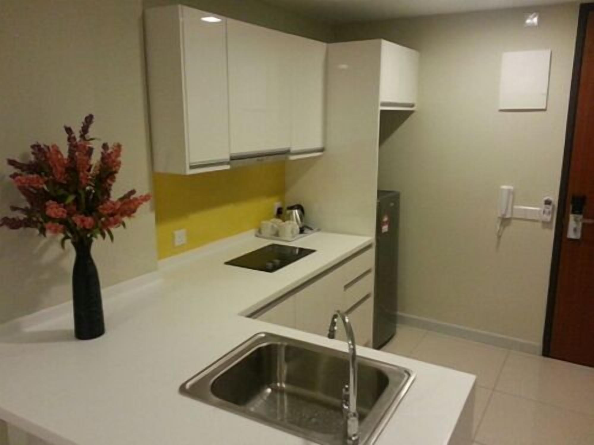 A modern kitchen with white cabinets, a stainless steel sink, and a yellow backsplash.