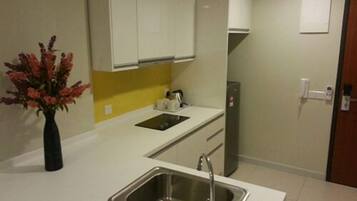 A modern kitchen with white cabinets, a stainless steel sink, and a yellow backsplash.