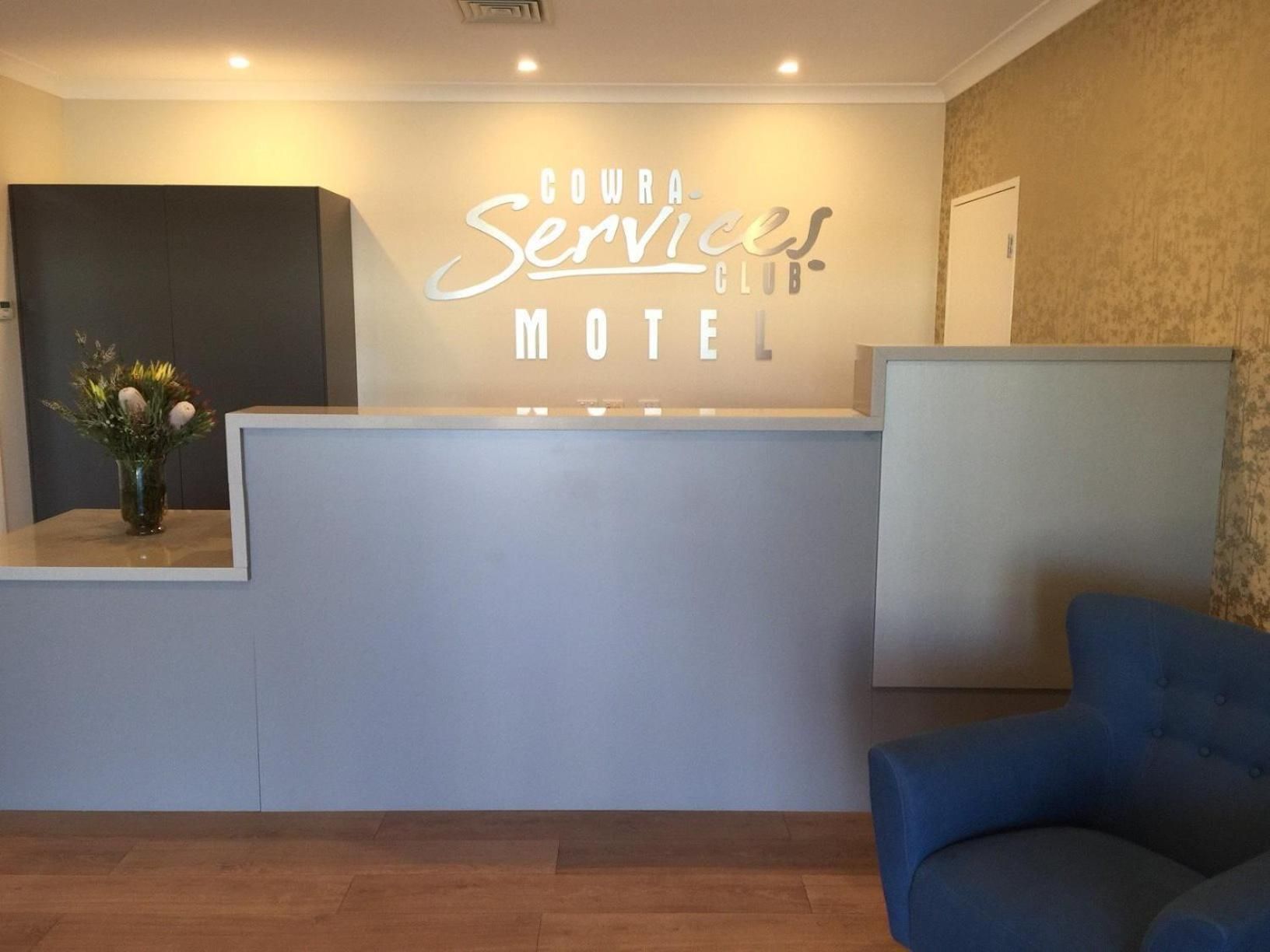 A reception desk with a sign that reads 'COWRA Services Club Motel.'