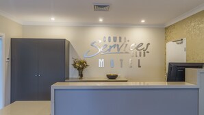 Un comptoir d’accueil avec une enseigne indiquant : « COWRA Services Club Motel ».