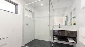A modern bathroom with a glass-enclosed shower, a white sink, and a mirror above the vanity.