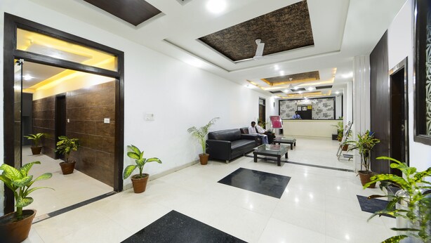 A modern lobby with a reception desk, seating area, and potted plants. - Hotel East Gate (Agra)
