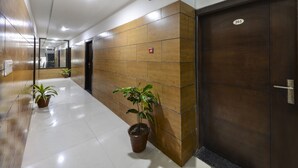 A hallway with a tiled floor, wooden panels on the walls, and a door marked with the number 203. - Hotel East Gate (Agra)