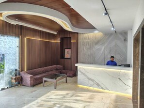Una moderna zona de recepción con un mostrador de mármol, techo de madera y un sofá modular.