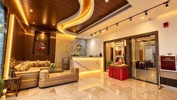 A hotel lobby with a reception desk, a sofa, a dining area, and a restaurant named 'Green Ginger Restaurant'.
