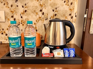 A tray with Bisleri water bottles, a coffee mug, a Prestige coffee maker, a Nescafe Classic coffee packet, and Nestle EveryDay milk packets. - Hotel Taj Heights (Agra)