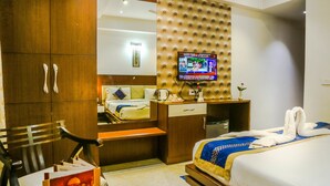 A hotel room with a bed, a desk, a television, and a wardrobe. - Hotel Taj Heights (Agra)