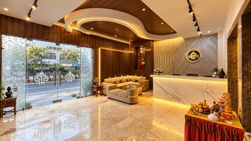 A modern hotel lobby with a reception desk, seating area, and a glass entrance.