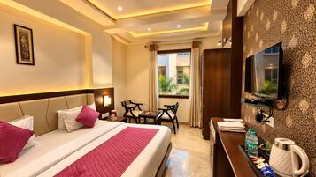 A hotel room with a bed, bedside tables, a desk with a television, a coffee maker, and a window with curtains.