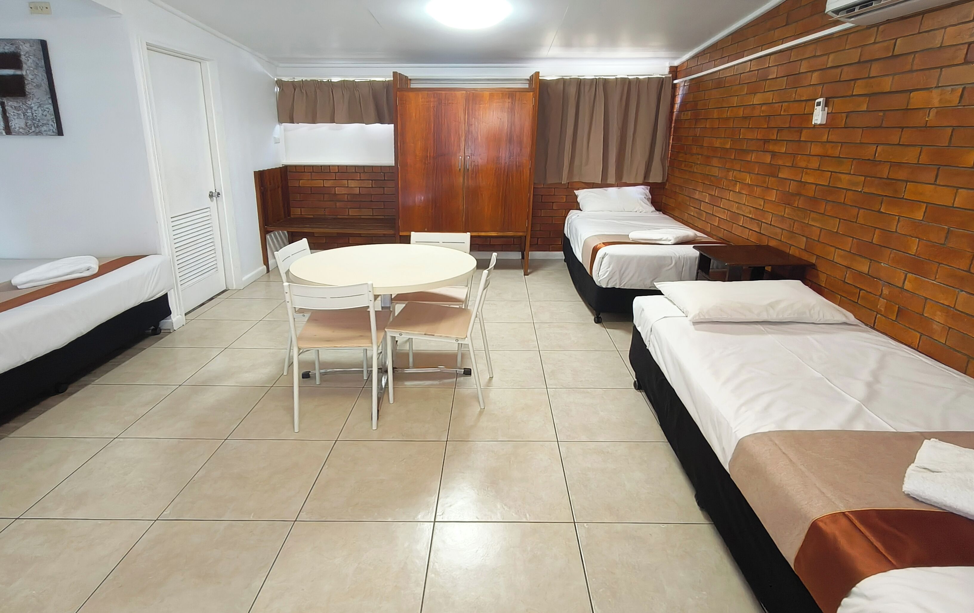 A hotel room with a bed, a table, chairs, and a wardrobe.