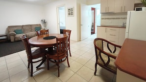 A compact living space with a dining area, kitchenette, and a sofa. - Motel Myall (Dalby)