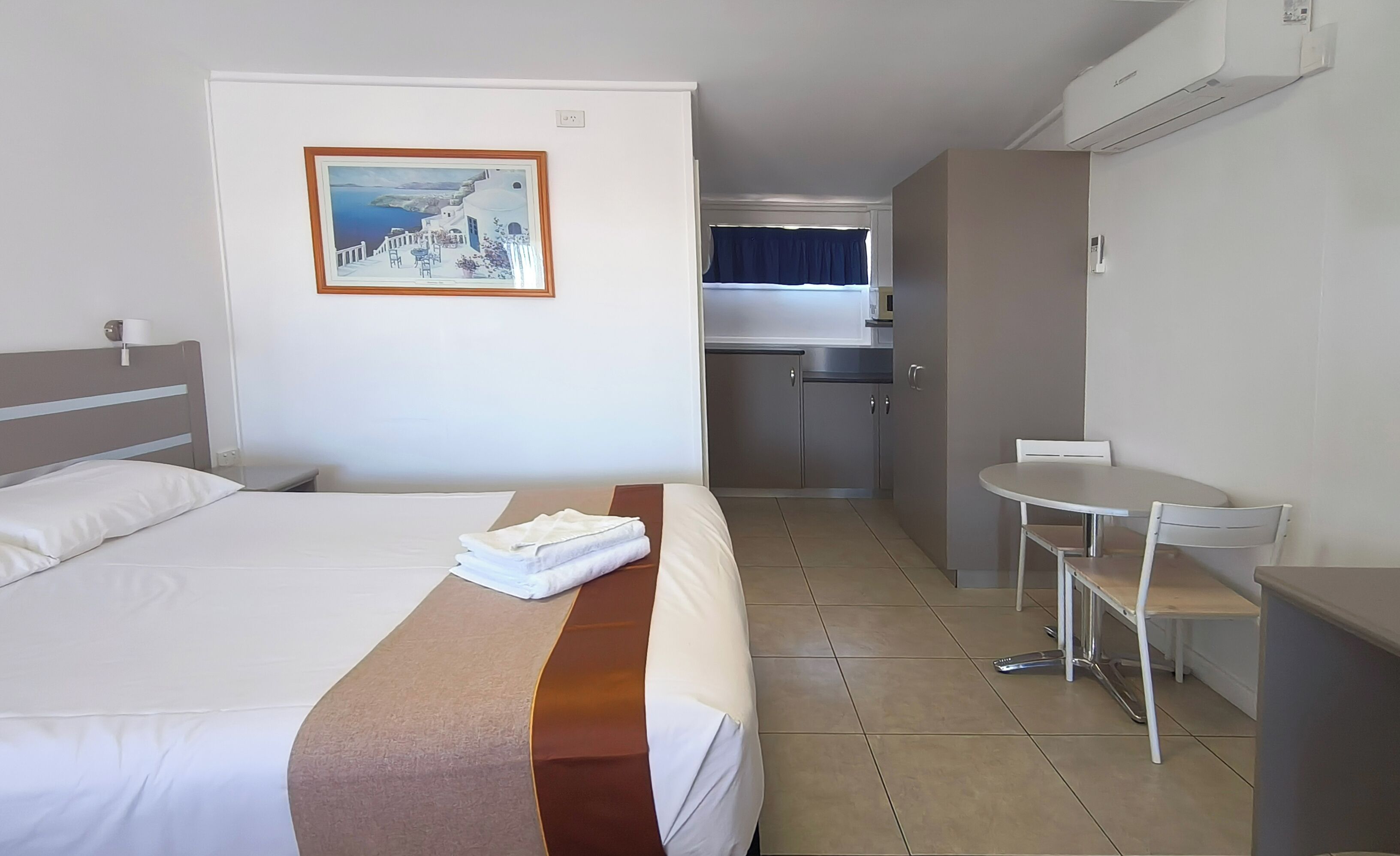 Una camera d'albergo con un letto, un angolo cottura, un tavolo da pranzo e una sedia.