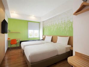 Une chambre d’hôtel avec deux lits, un bureau et une chaise.