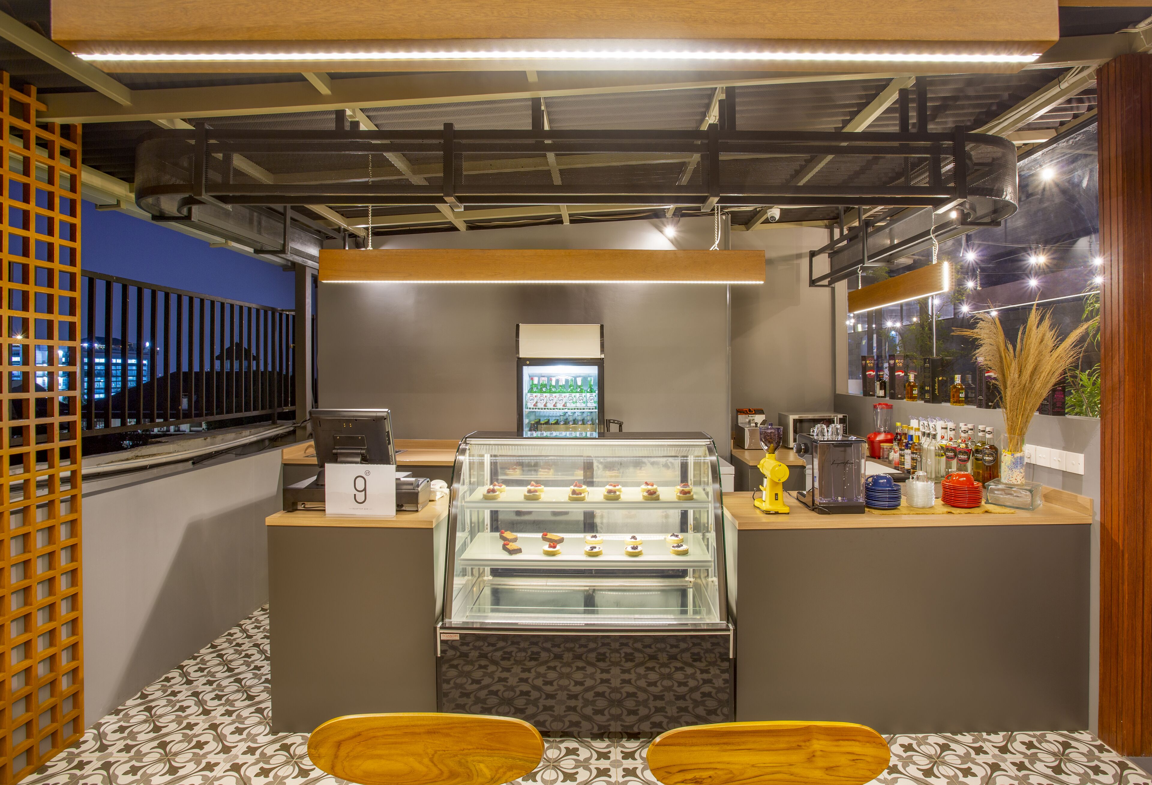 Un comptoir de boulangerie avec une vitrine remplie de pâtisseries, une caisse enregistreuse et un réfrigérateur.