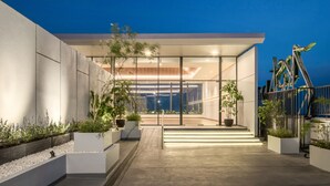 Een modern huis met een glazen gevel, buitenverlichting en een minimalistisch ontwerp.