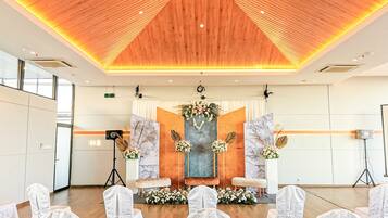 A spacious hall with a wooden ceiling and a stage with floral decorations.