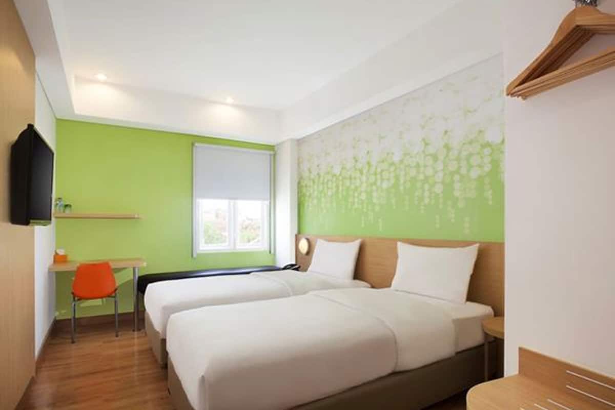Een hotelkamer met twee bedden, een bureau en een stoel.