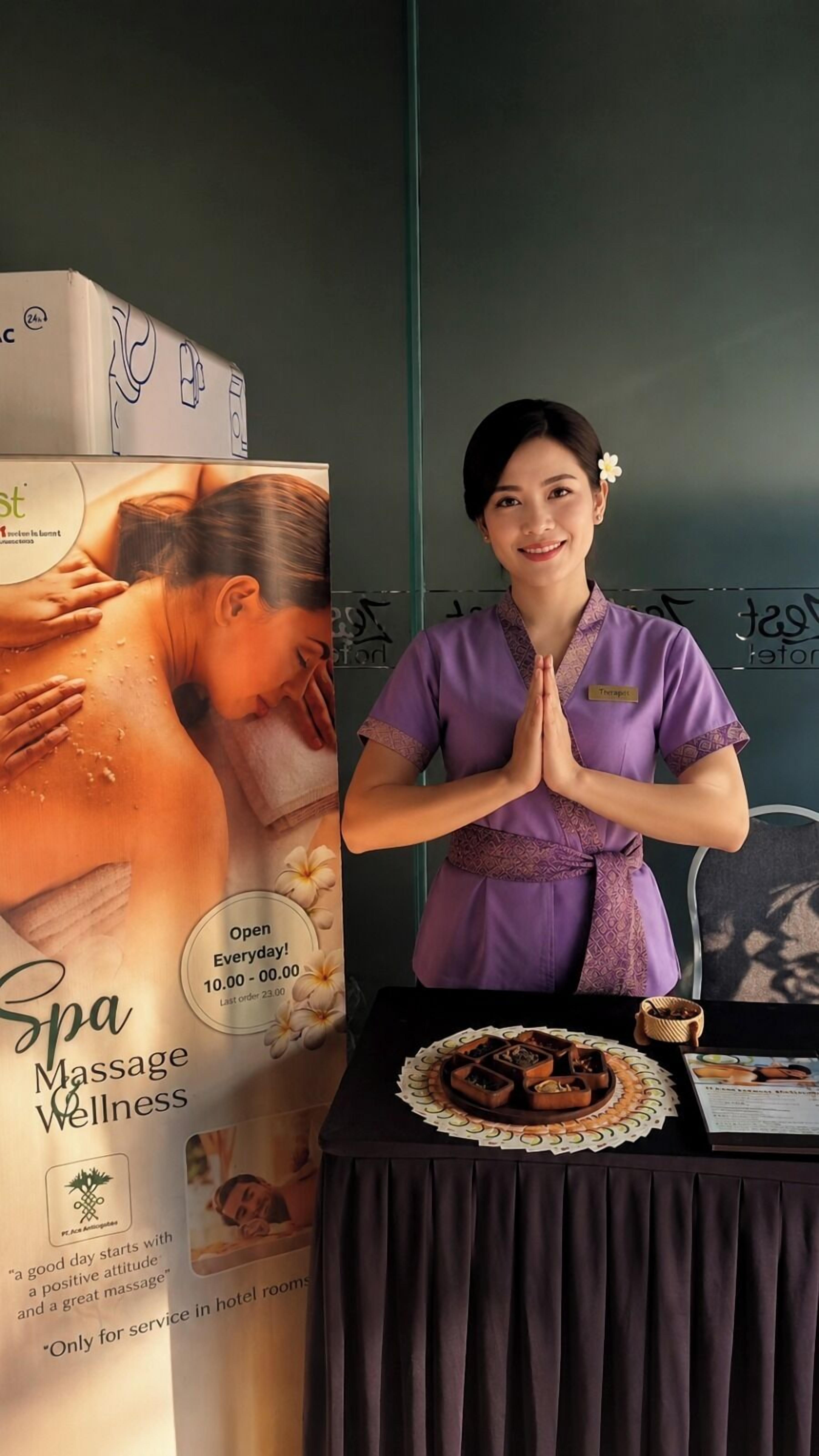 A spa service area with a massage poster, a table with a tray of snacks, and a person in a purple uniform.