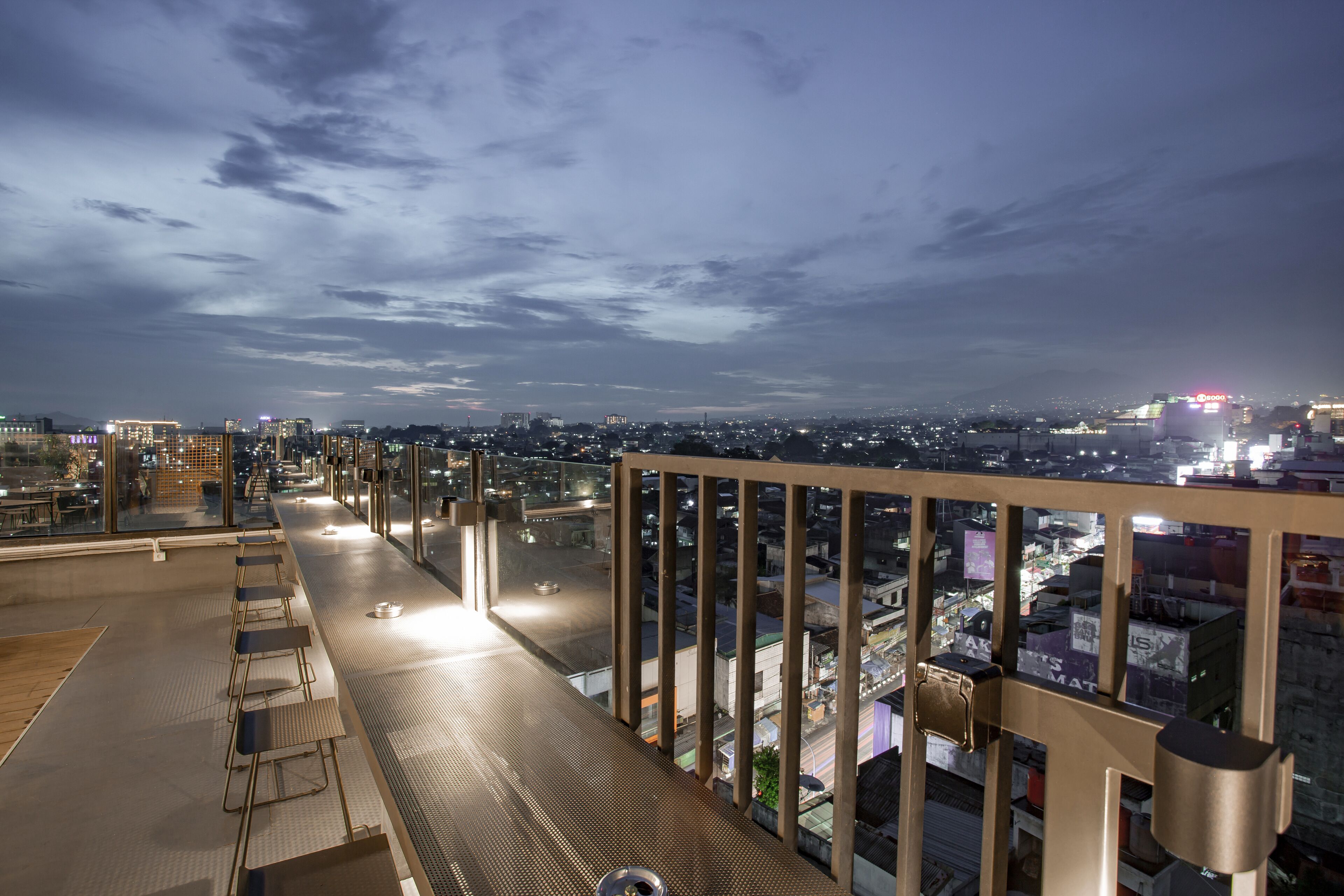 A rooftop terrace with a view of the cityscape at night.