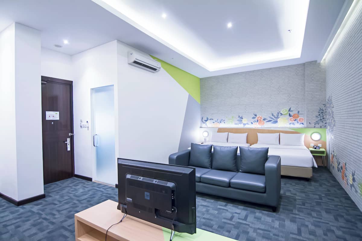 Une chambre d’hôtel avec un lit, un canapé, une télévision et un bureau.
