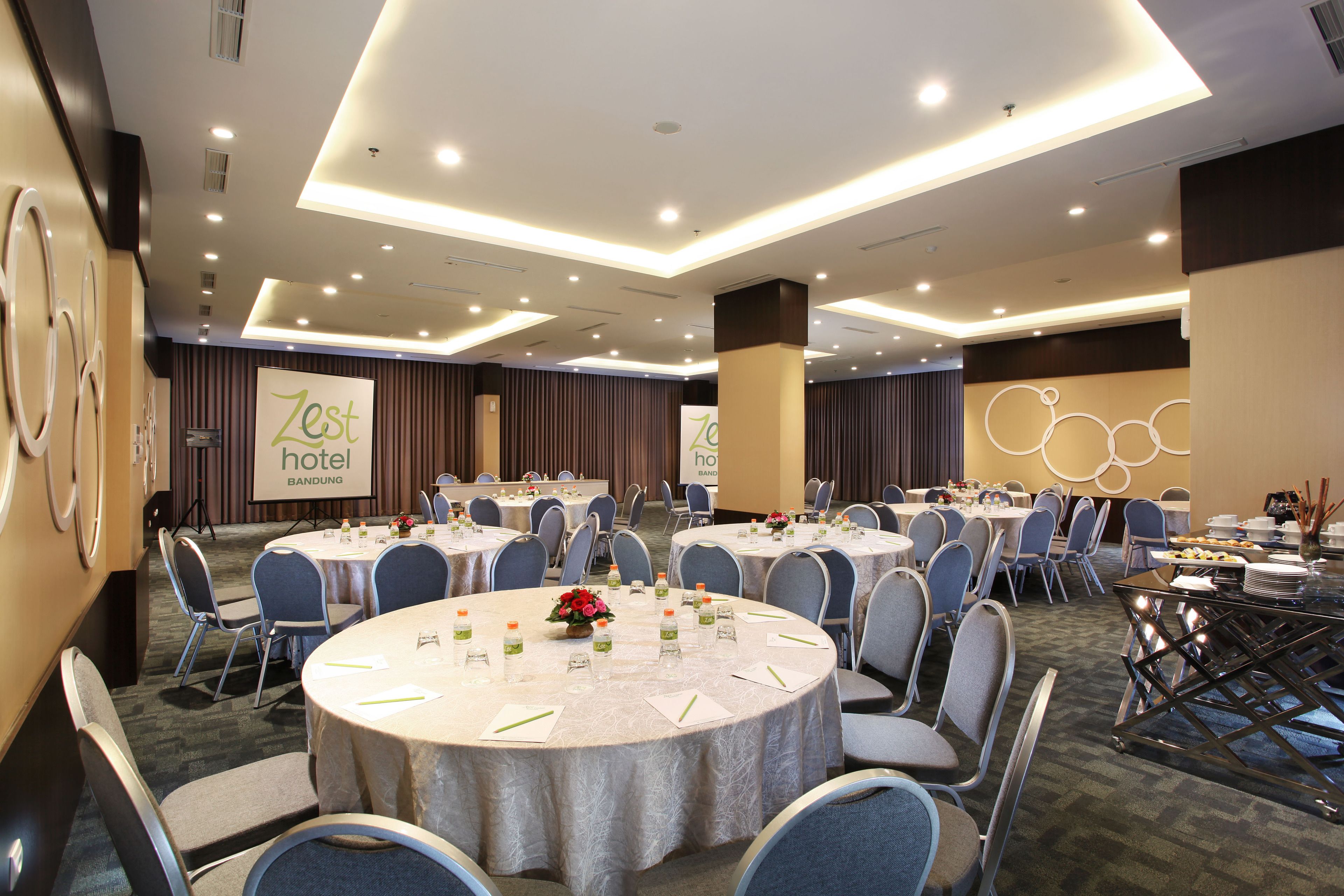 A conference room with round tables, chairs, and a stage with a podium.