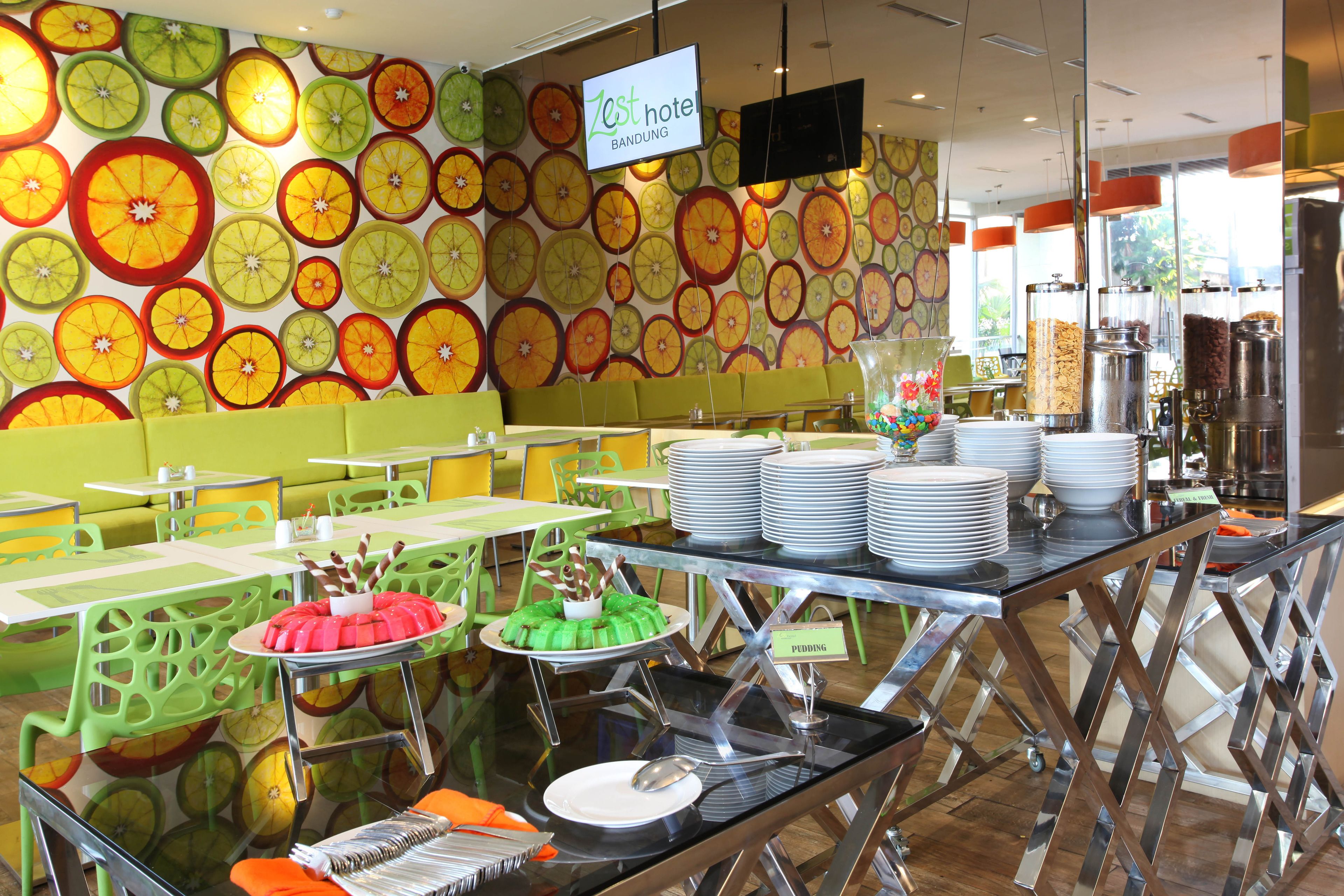 Zona de bufé con diversos alimentos y una pared decorada con rebanadas de fruta.