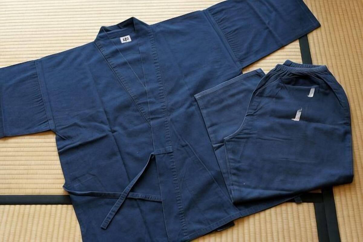 A blue shirt and pants laid out on a tatami mat.