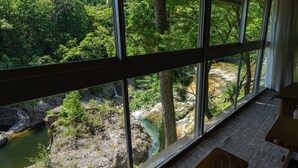 Una habitación con un amplio ventanal que da a un área boscosa y un río.