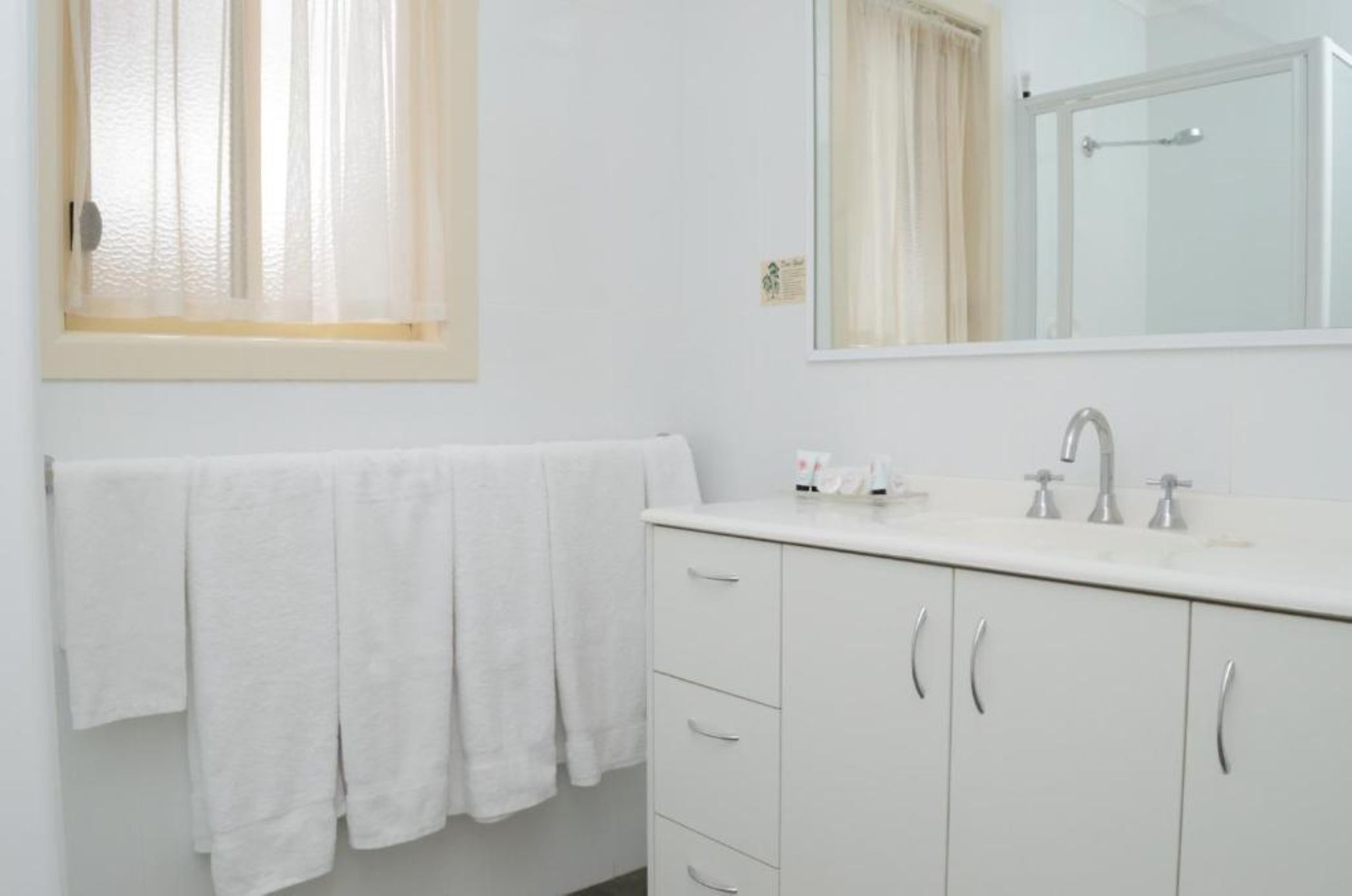 A bathroom with a white sink, mirror, and towel rack.