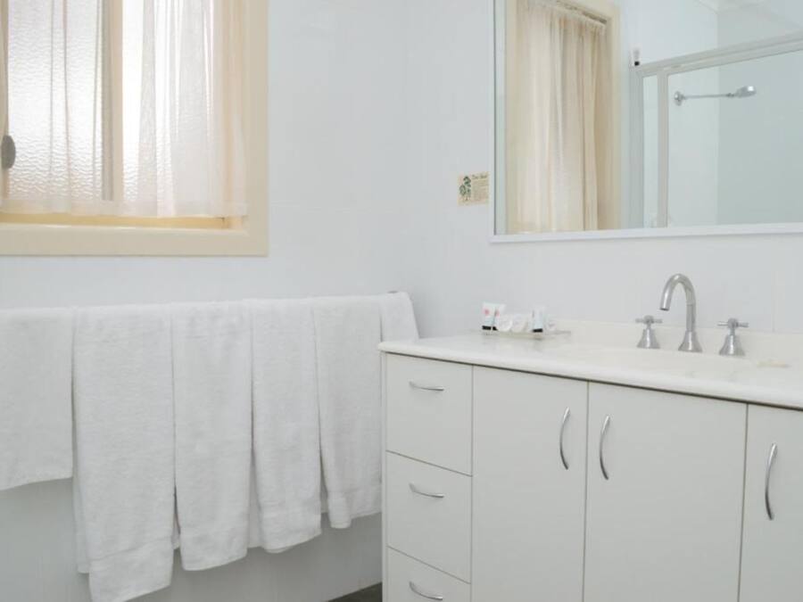 A bathroom with a white sink, mirror, and towel rack.