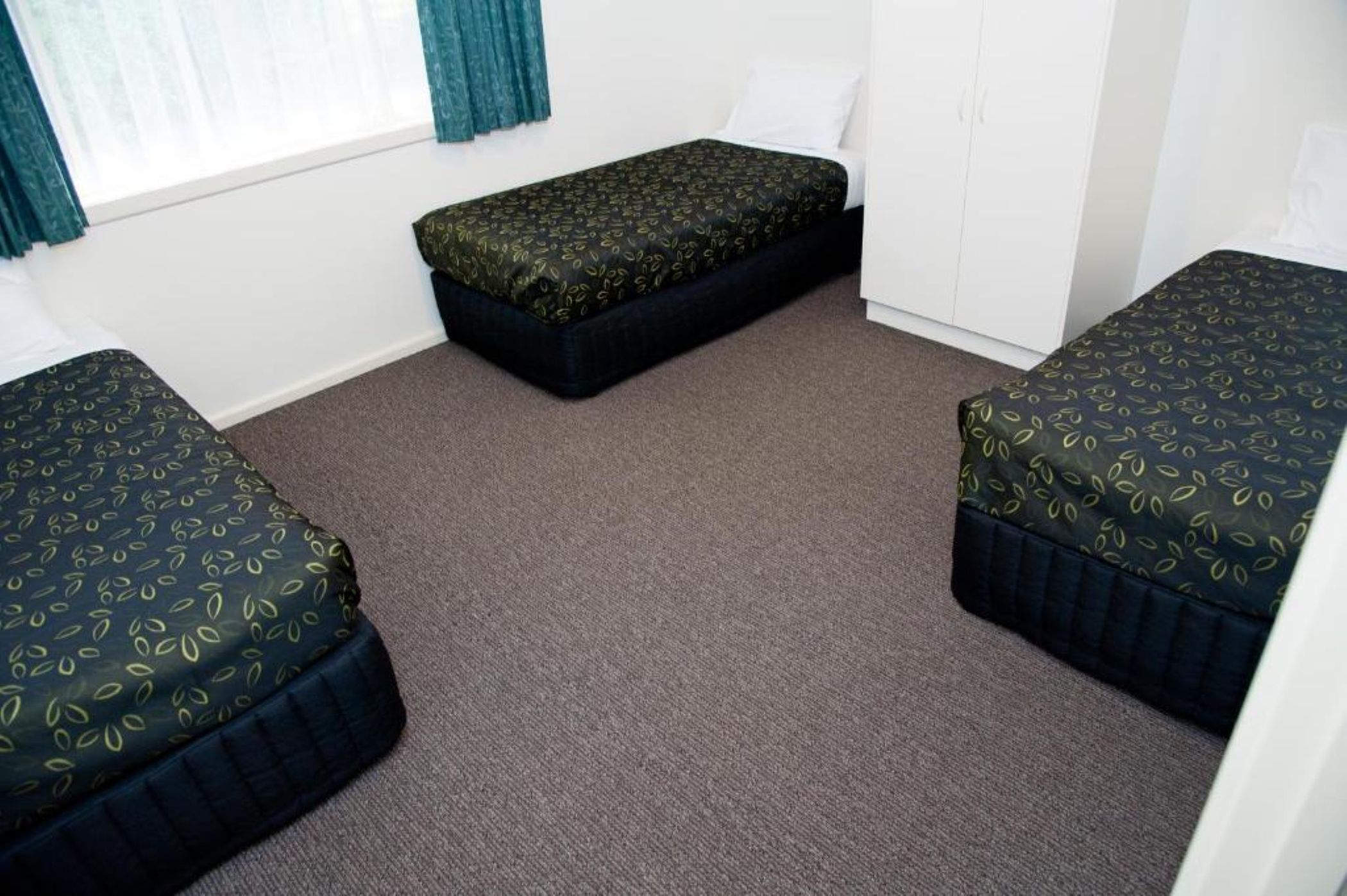 A room with two single beds, a bench, and a wardrobe.
