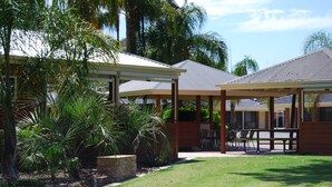 A covered outdoor area with seating and a stone planter with palm trees.