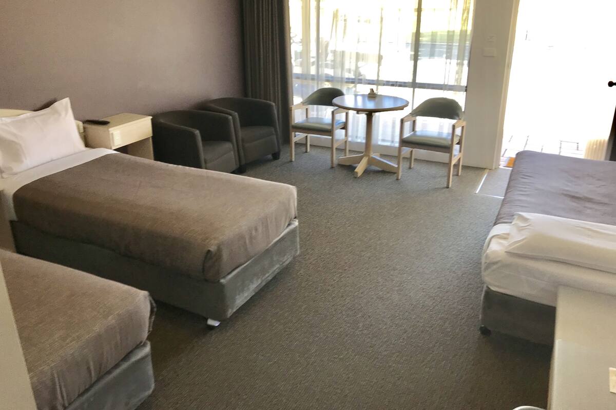 A hotel room with a bed, two armchairs, a small table, and a sofa.