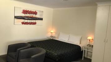 A bedroom with a bed, two bedside tables with lamps, a wardrobe, and a painting on the wall.